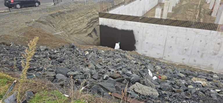 Waterproofed foundation wall behind a bed of drain rock