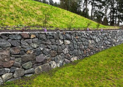 Natural stone retaining wall in Victoria, BC, built for erosion control and landscaping.