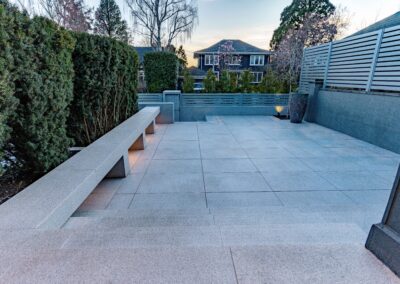 Modern granite hardscape installation with large-format pavers, stair treads, and privacy wall at a residential property in Victoria, BC.