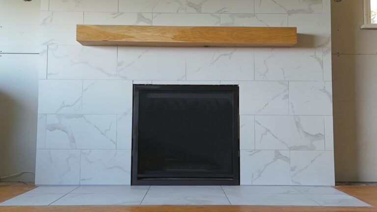 Modern fireplace finished in Carrara porcelain tile with a floating mantel