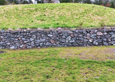 Natural stone retaining wall in Victoria, BC, built for erosion control and landscaping.