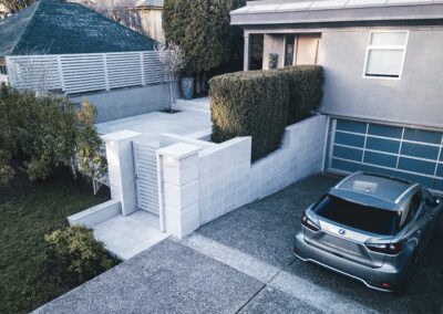 Modern granite hardscape installation with large-format pavers, stair treads, and privacy wall at a residential property in Victoria, BC.
