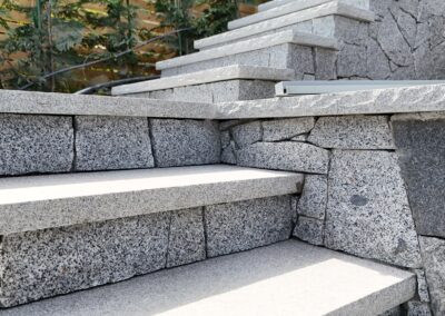 Granite stone steps built with natural granite treads at a coastal residential property, showcasing precision stone installation and ocean view landscaping.