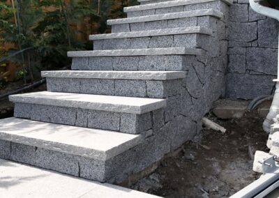 Granite stone steps built with natural granite treads at a coastal residential property, showcasing precision stone installation and ocean view landscaping.