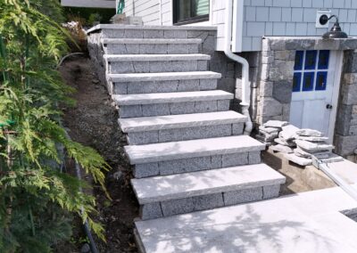 Granite stone steps built with natural granite treads at a coastal residential property, showcasing precision stone installation and ocean view landscaping.