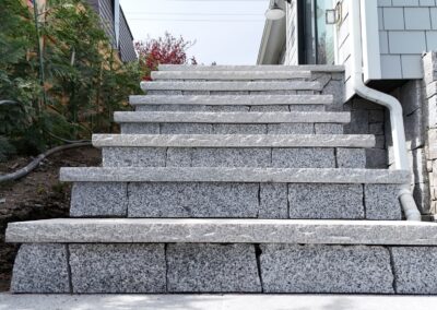 Granite stone steps built with natural granite treads at a coastal residential property, showcasing precision stone installation and ocean view landscaping.