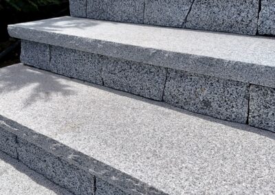 Granite stone steps built with natural granite treads at a coastal residential property, showcasing precision stone installation and ocean view landscaping.