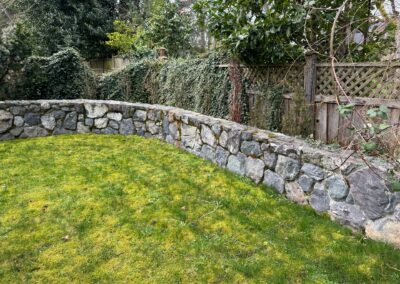 Natural stone retaining wall installed by Orca Masonry in Victoria, BC, providing structural support and a timeless aesthetic for residential landscaping.