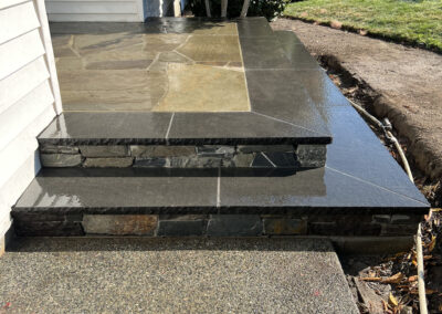 Natural stone porch and steps installation with dark stone border and mosaic-style flagstone center, completed in Victoria, BC.