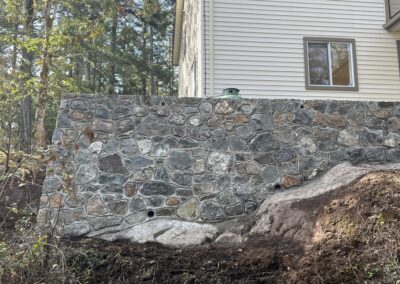 Custom-built stone retaining wall for an elevated home, providing structural support and durability, installed by Orca Masonry in Victoria, BC.