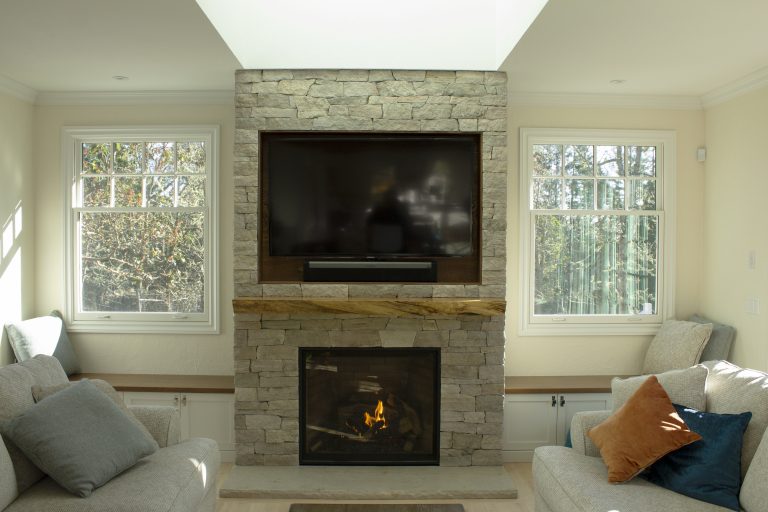 Natural limestone veneer fireplace with a marble hearth in a bright living room