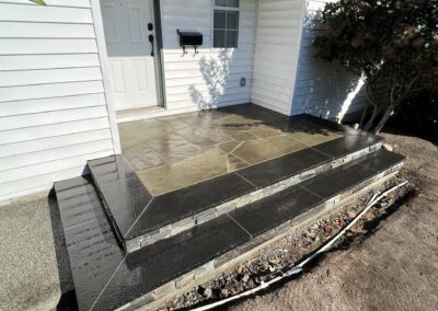 Natural stone porch and steps installation with dark stone border and mosaic-style flagstone center, completed in Victoria, BC.