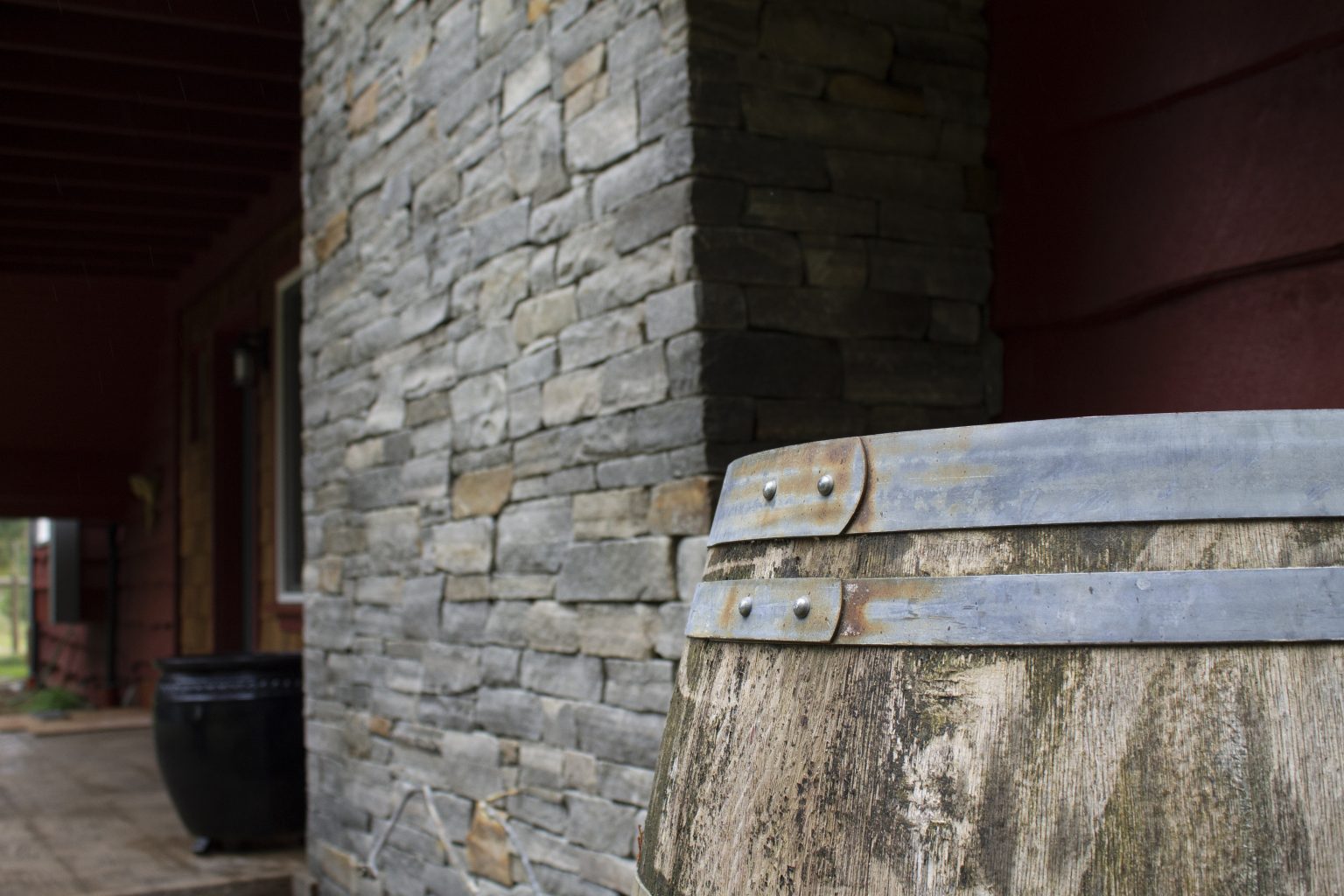 Close-up of a hand-laid ledgestone column beside an old oak barrel