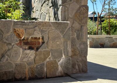 Rustic stone bench and wall installation by Orca Masonry in a landscaped outdoor space in Victoria, BC