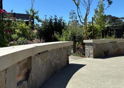Rustic stone bench and wall installation by Orca Masonry in a landscaped outdoor space in Victoria, BC