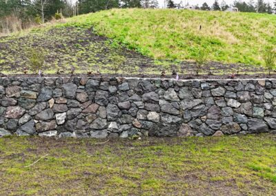 Natural stone retaining wall in Victoria, BC, built for erosion control and landscaping.