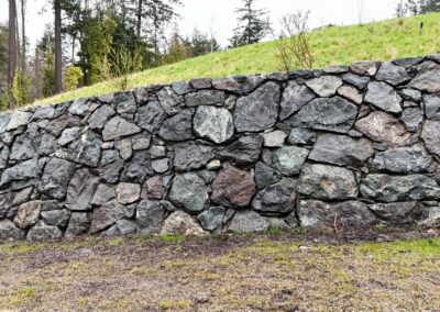 Natural stone retaining wall in Victoria, BC, built for erosion control and landscaping.