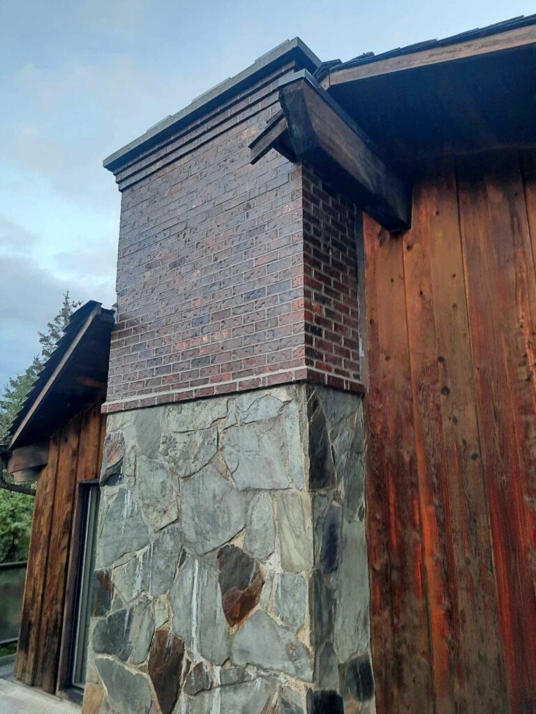 Dark flashed Covington brick chimney rising from a stone base