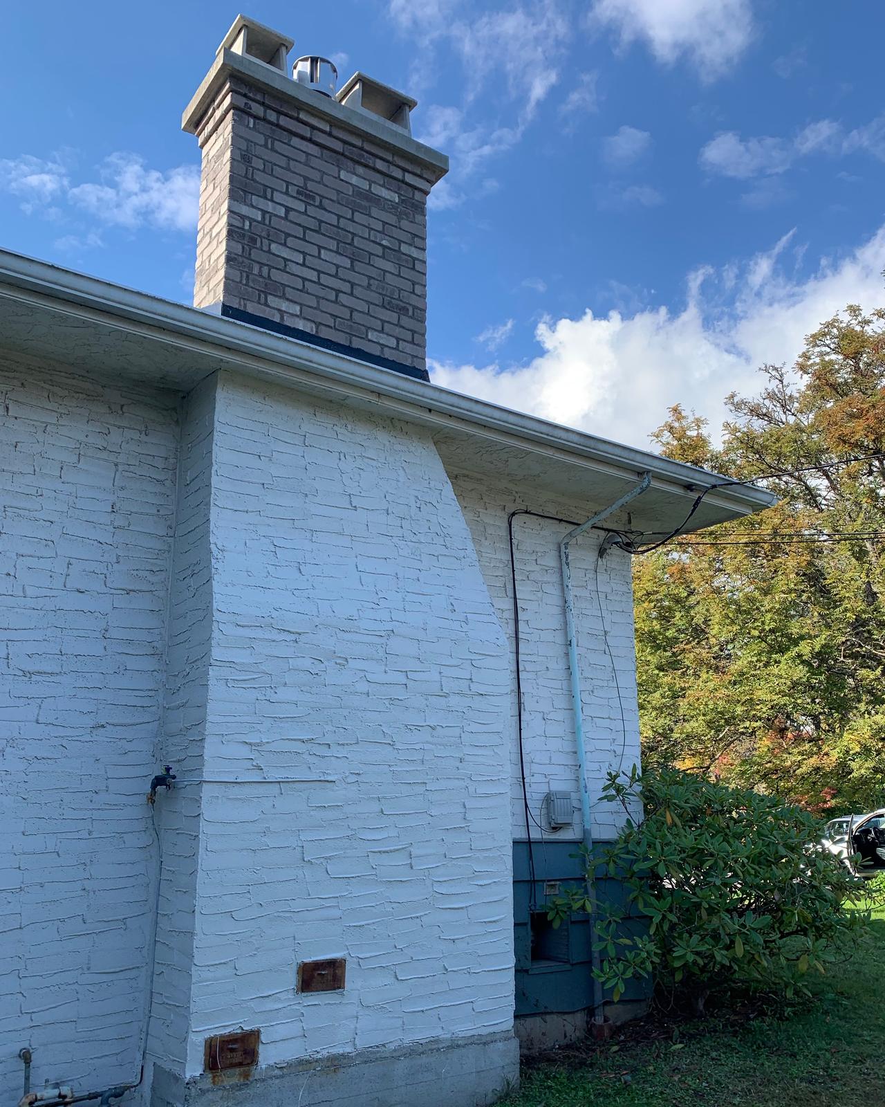The same chimney after Orca Masonry rebuilt it: new grey-brown brick stack with flue covers