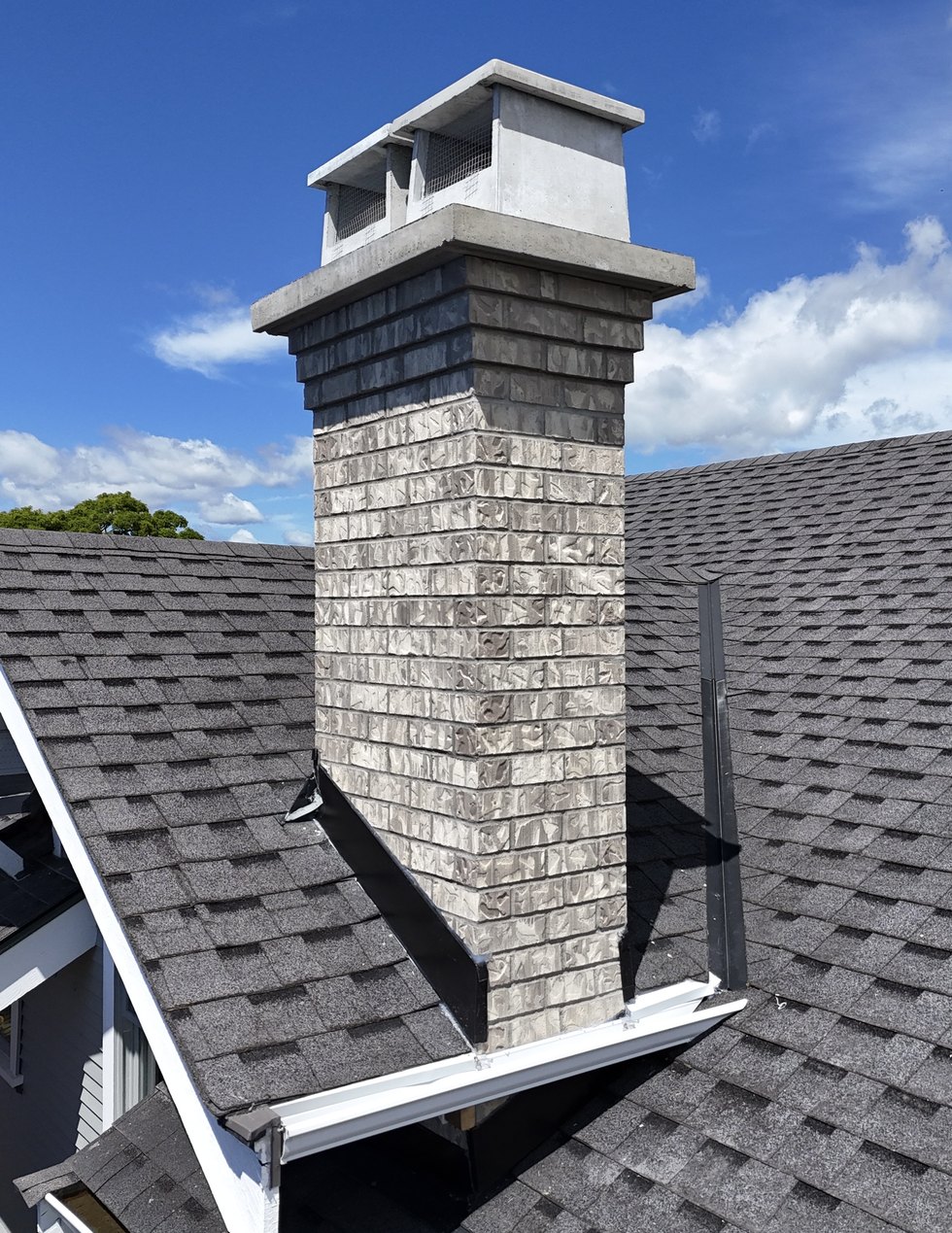 Brick chimney with a precast concrete cap and screened flue covers