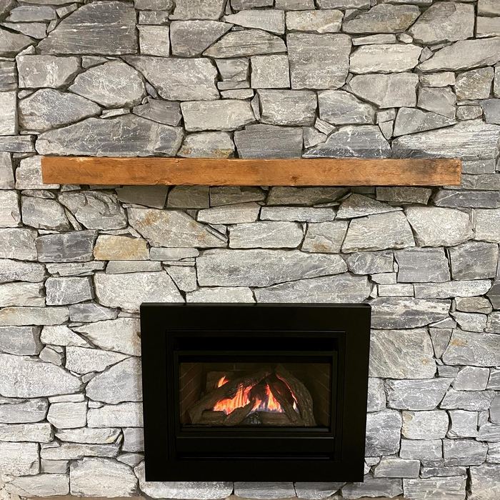 Grey ledgestone fireplace wall with a gas insert and a rustic wood mantel