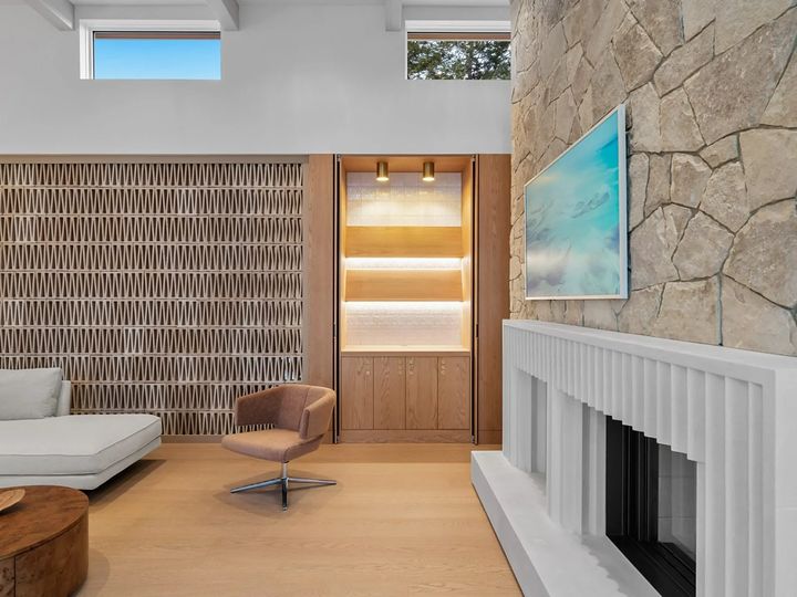 Close-up of a natural stone wall and a fluted white fireplace surround