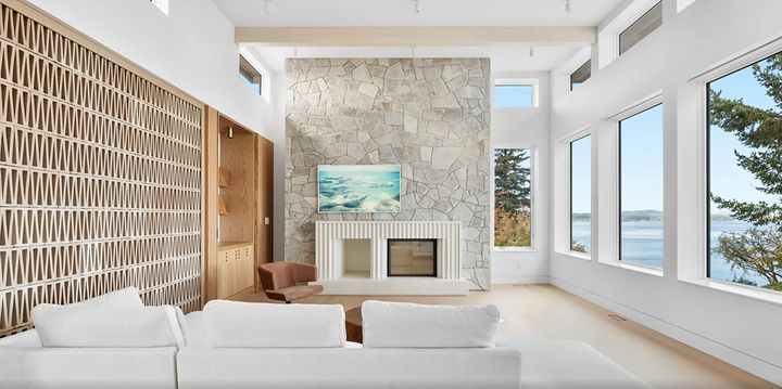 Bright living room with a natural stone fireplace wall and a fluted white surround