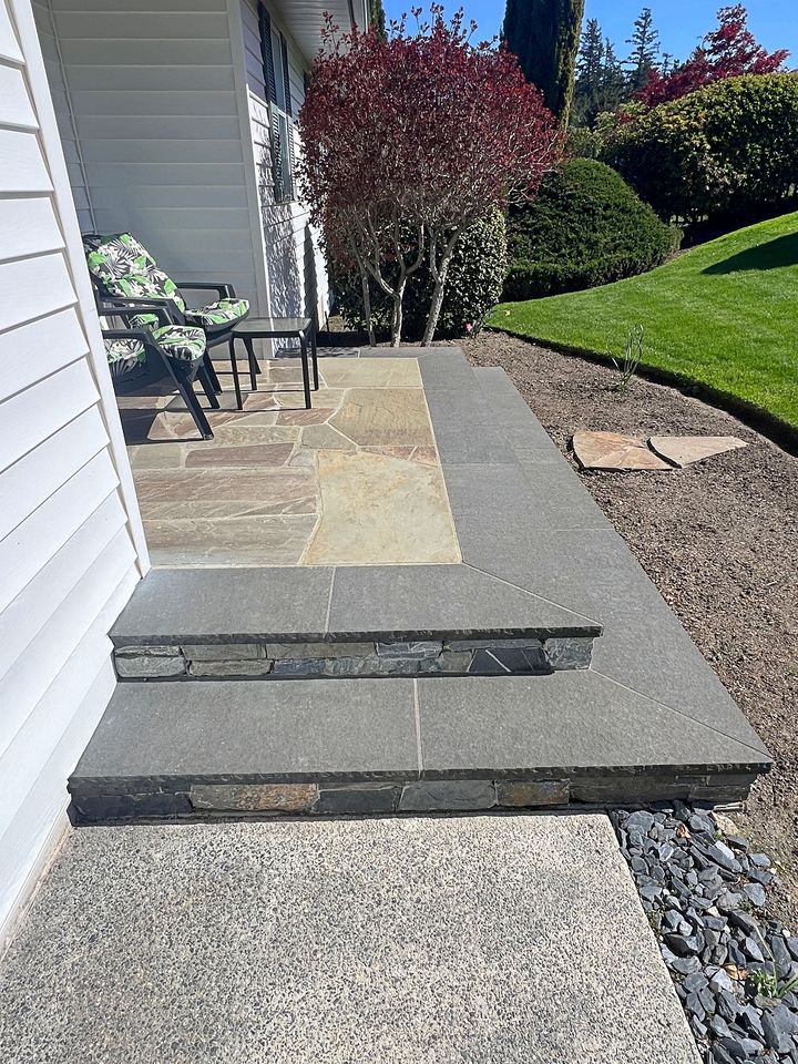 Flagstone porch with charcoal stone treads and a ledgestone riser seen along the side of the house