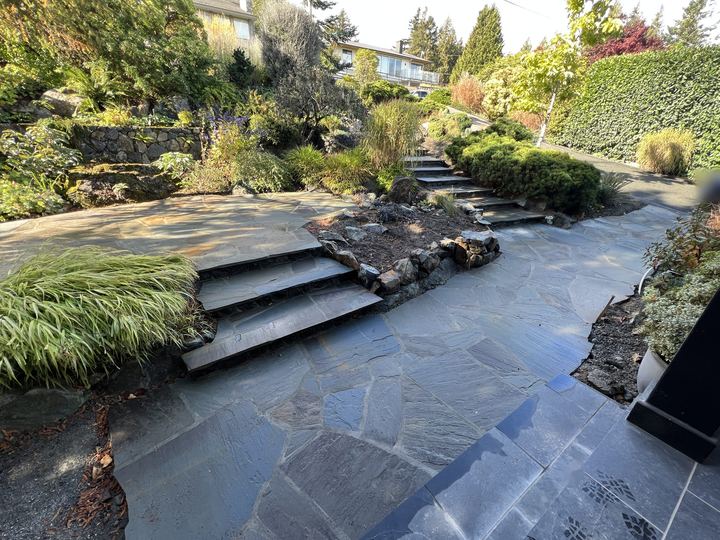 Wide flagstone patio with stone steps rising through a planted garden