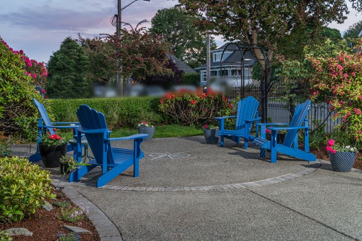 Round exposed aggregate patio with a paver border, a compass rose inlay and blue Adirondack chairs