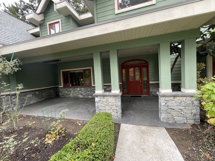 Covered front porch in large-format tile, with stacked stone veneer on the low walls and column bases