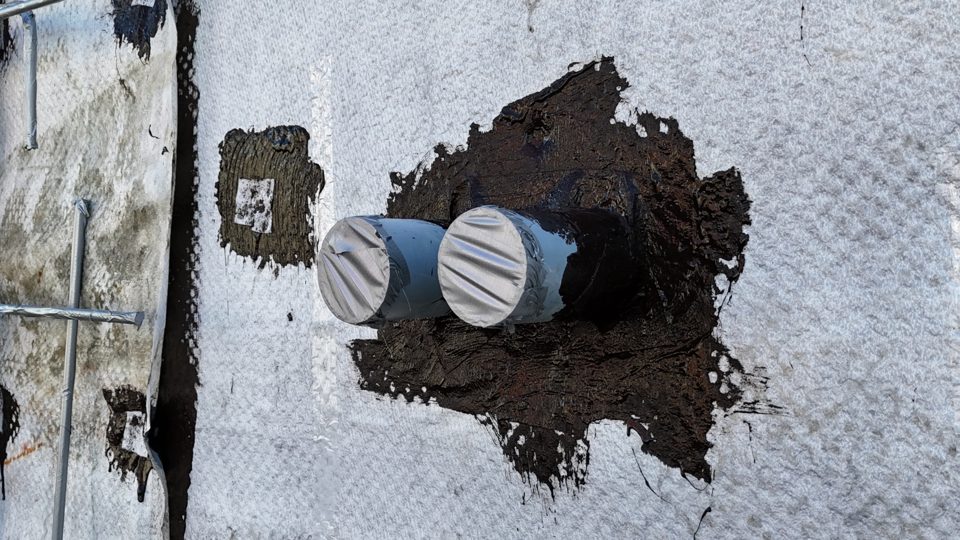 Membrane detailing around two pipe penetrations through a foundation wall