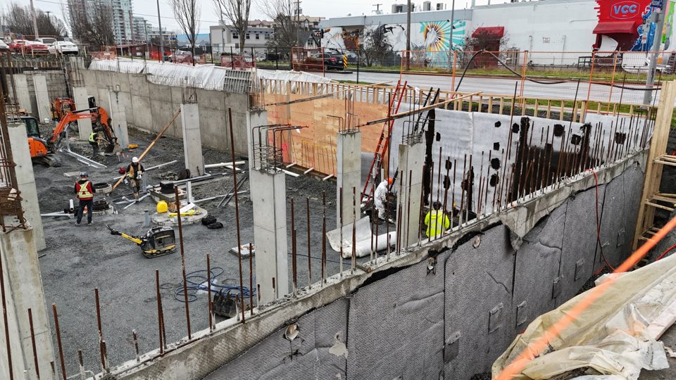 Large commercial foundation site with waterproofed walls and crews at work