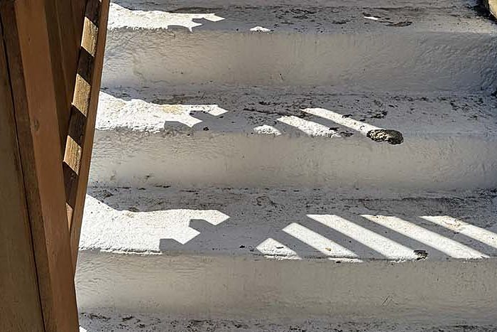 Concrete steps with a thin painted coating cracking and flaking