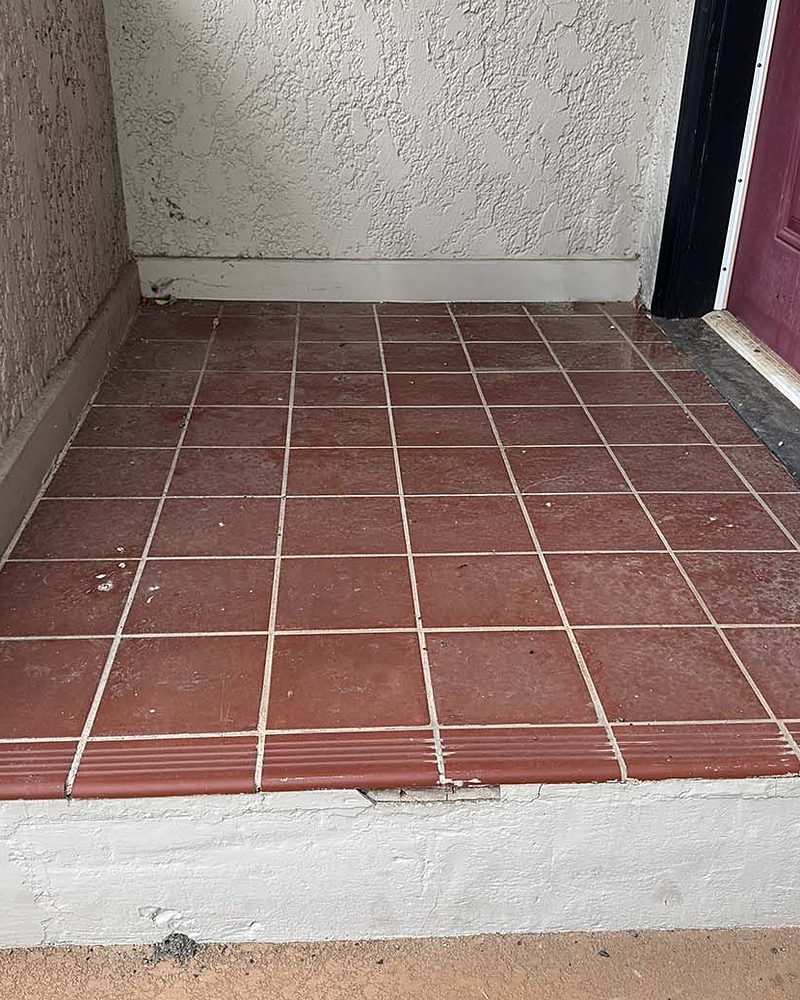 A covered landing and step with old red tile, before StepClad