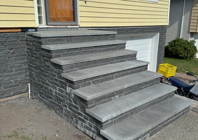Custom stone steps with dark grey cladding installed on a residential entrance in Victoria, BC.